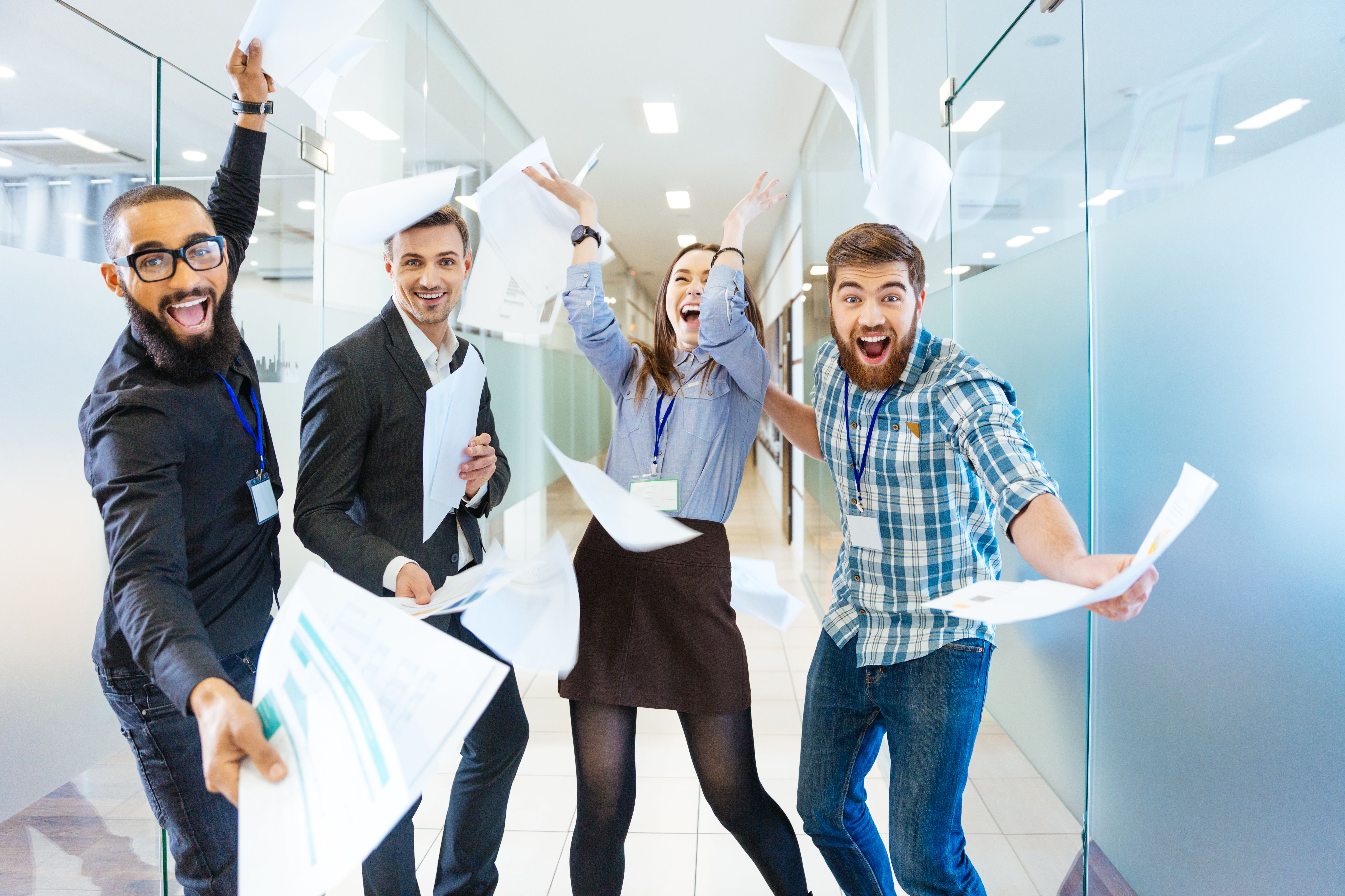Group of joyful excited business people throwing papers and having fun